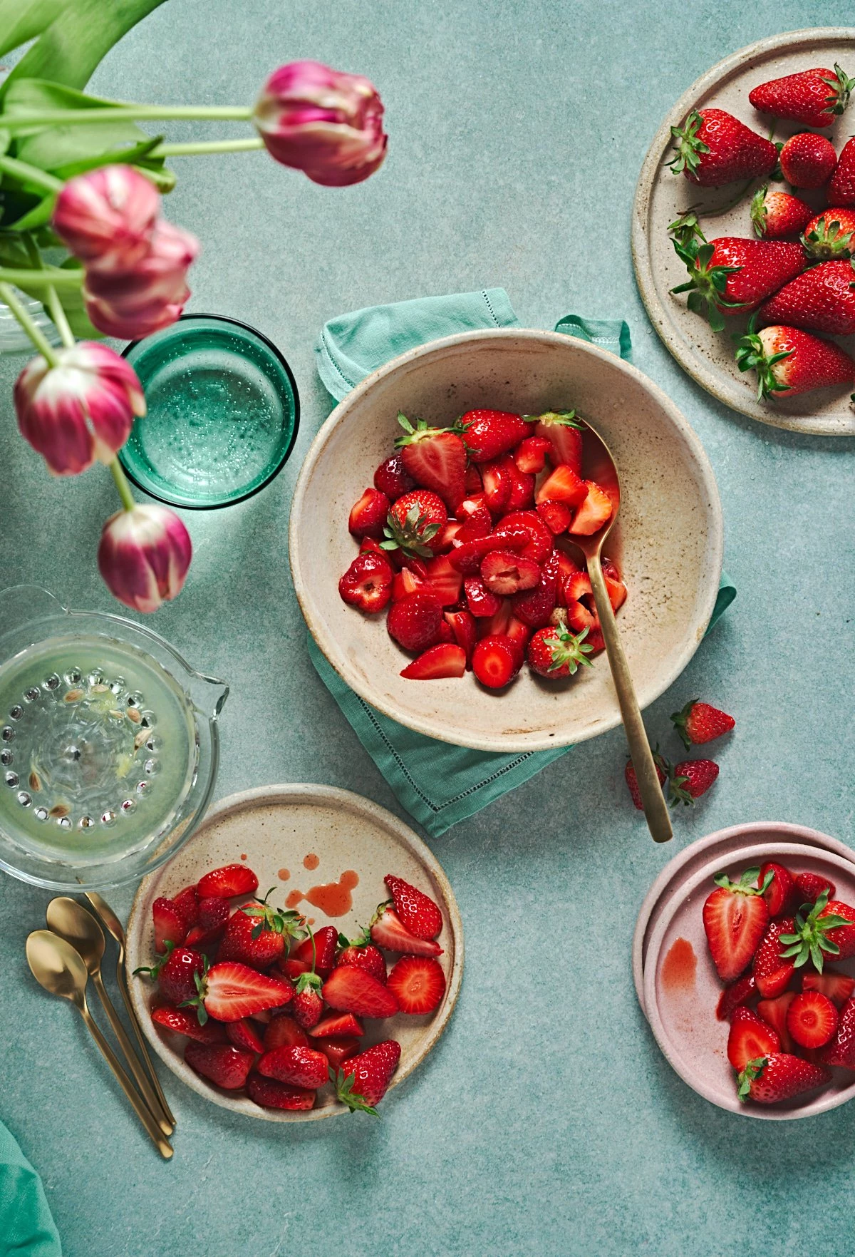 A spring table with fresh sliced strawberries, arranged on plates in soft tones. The light gently il...