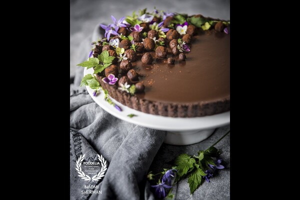 This cardamom infused chocolate tart was created after reading a food thesaurus which listed creative flavour pairings.<br />
It's baked with a grain free crust and decorated with garden flowers and truffles