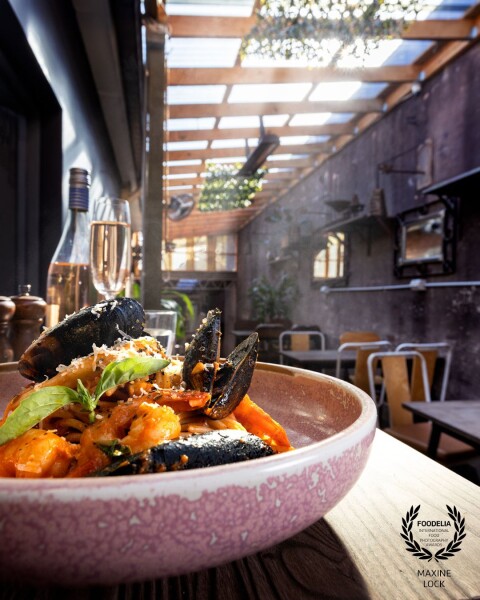 Photographing a beautifully styled pasta dish in a rustic restaurant setting, while incorporating sunlight into the image for a more vibrant feel.