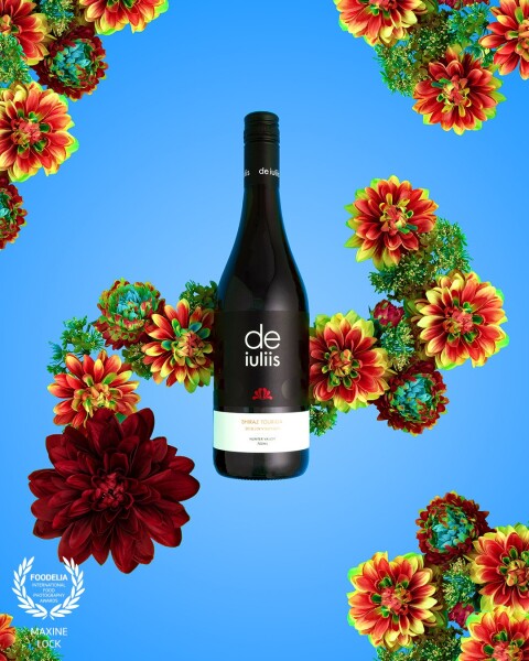 A bottle of red wine photographed with artificial flowers, and then multiplied to create further effects around the frame of the image in post-production.