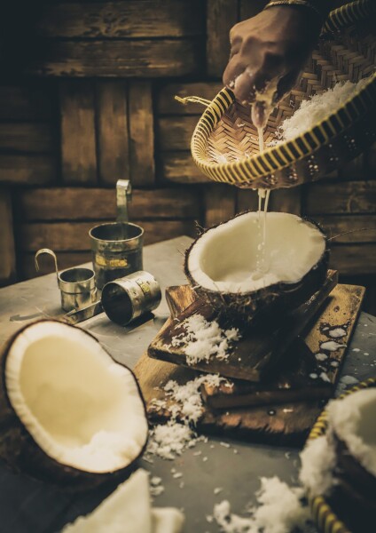 Coconut milk is one signature ingredient in Indonesian cuisine. Using freshly made coconut milk is still preferred by some people, even though it is a pretty exhausting process. 

Here the milk is extracted by hand-squeezing the grated coconut that has been mixed with warm water. A traditional bamboo strainer specially made for coconut milk is used to catch the loose coconut from falling into the extracted liquid. A set of traditional tin measuring cups commonly used to measure coconut milk is shown in the scene.