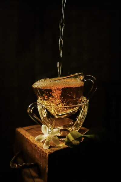 Jasmine Tea, or locally known as Teh Melati, is a popular kind of tea in Indonesia. This brewed tea is poured  into stacked tea cups. Some bubbles were forming as results of pouring from a distance. Decorated with a  jasmine flower and its leaves, picked from my home garden.