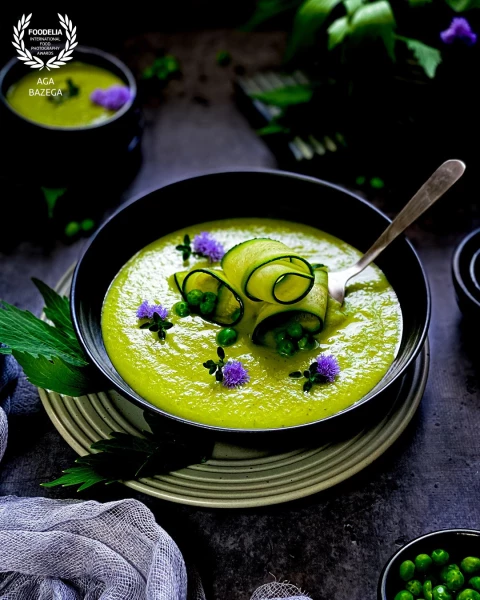 Green pea creamy soup served with edible flowers and thyme. Image created for photography challenge. Captured with a natural light.