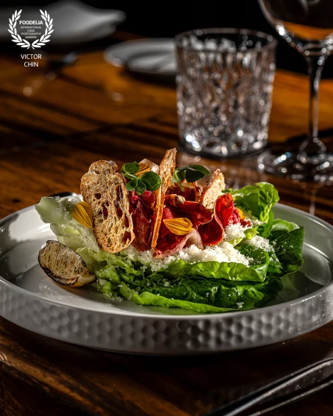 A meticulously crafted shot for a high-end restaurant, capturing a salad artfully shaped like a croi...