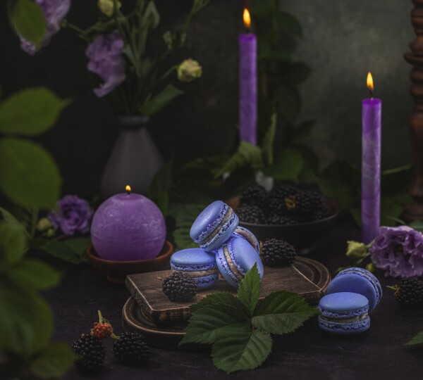 Violet macarons and blackberries surrounded purple candles and Eustoma or lisiant. Macarons is a very delicious french delicate dessert. Shooting for pâtisserie, local Ukrainian business.