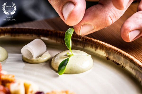 The chef's finishing touch completes the culinary work of art.  The delicate green leaf releases an inviting touch of color.  A simple but elegant gesture<br />
https://www.instagram.com/foodphotographyroma?igsh=ZjN0OXUyMHhxcXdi