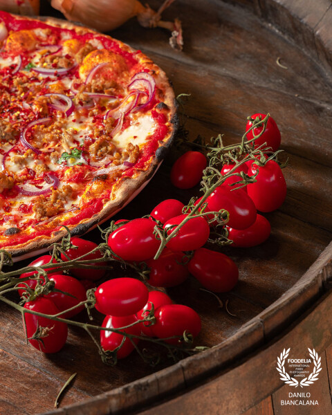 A wonderful pizza photographed at  near some lovely tomatoes, photo taken during a shooting for soci...