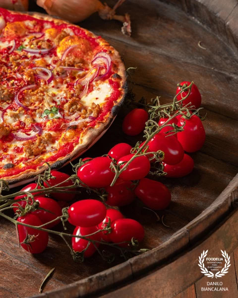A wonderful pizza photographed at  near some lovely tomatoes, photo taken during a shooting for soci...