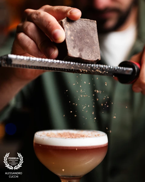 Bartender grinding chocolate on his personal new interpretation of a new york sour.