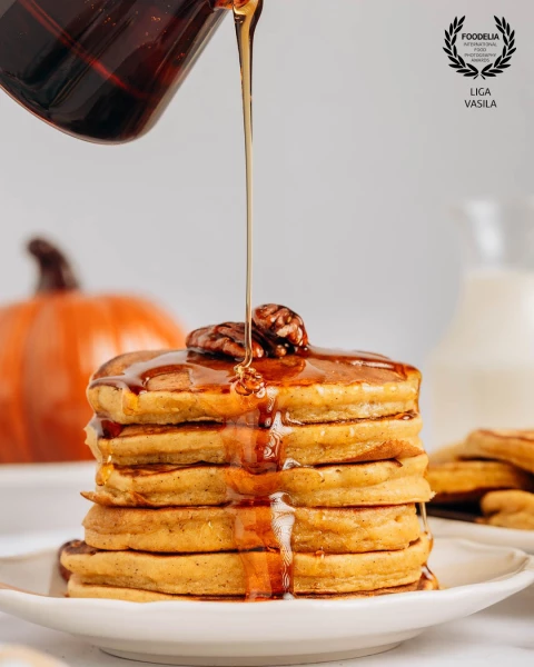 A personal food photography project highlighting pumpkin pancakes stacked high and bathed in rich, g...