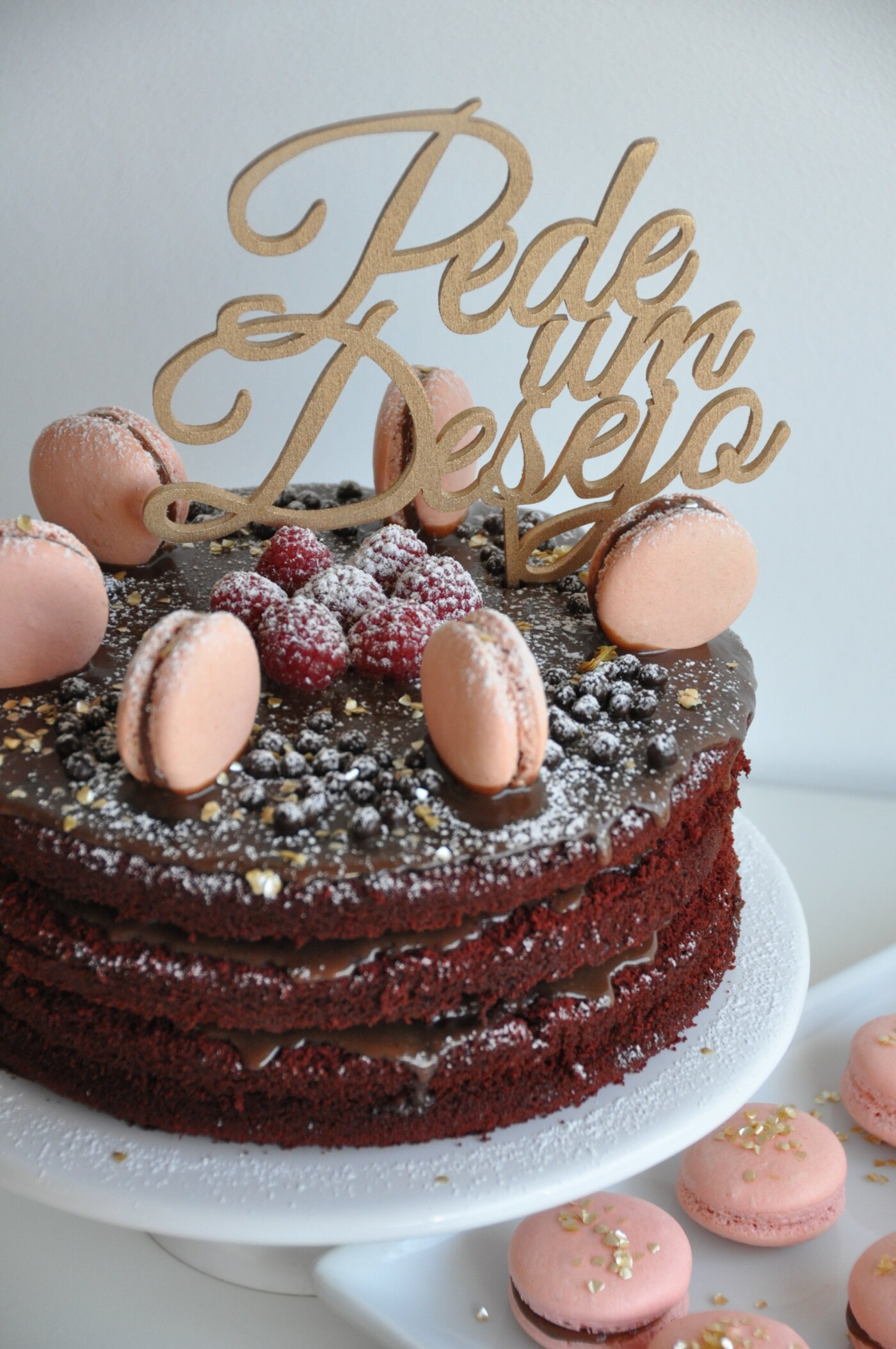 This is a birthday cake I have made for my mother-in-law. It was a red velvet cake, with raspberries, chocolate ganache and macarrons. I had the topper designed specially in Portuguese and it says "make a wish".