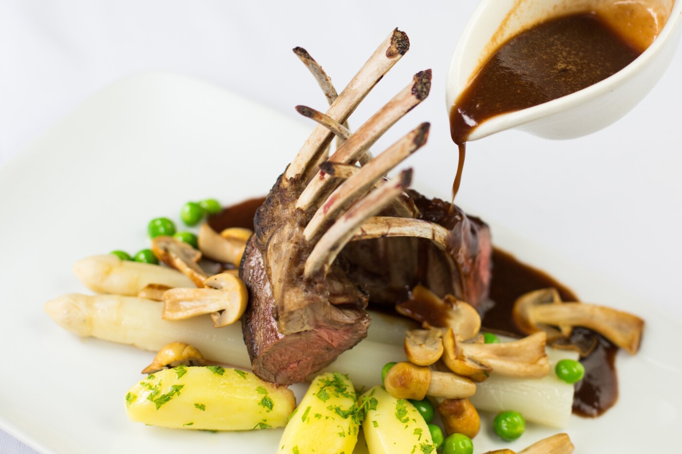 This photo is taken at Restaurant Vuur in Baarn, the Netherlands. The beautiful lambs rack with asparagus really stands out on the white background. Pouring the sauce over it gives the image just that extra dimension.