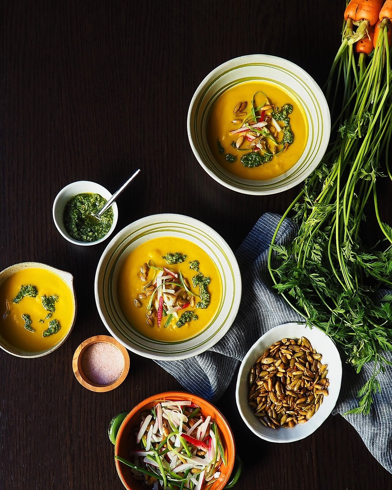 A cozy soup that nourishes and comforts. Creamy carrot soup with carrot top pesto made from fresh carrot leaves, radish salad topping and roasted pepitas for some crunch.