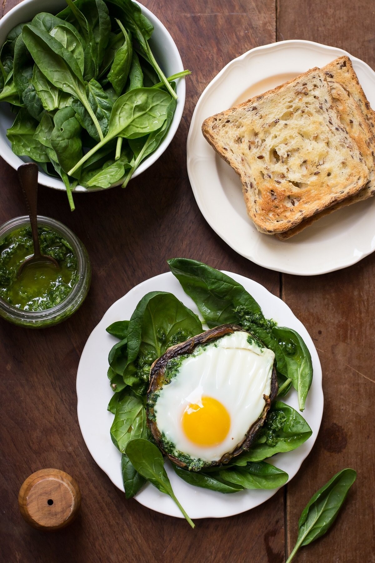 This a photo of a funny breakfast, where a big mushroom is used as an edible cup for an egg. I baked the egg in the mushroom with some parsley garlic sauce and serve on a spinach salad.