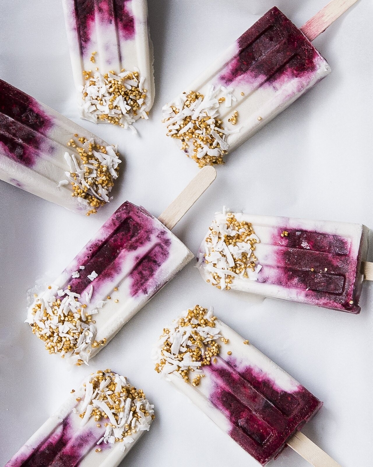 These coconut milk mixed berries popsicles dipped with toasted quinoa and shredded coconuts are the perfect elements for creating a modern palette of a clean background contrasting with punches of bold magenta hues. 