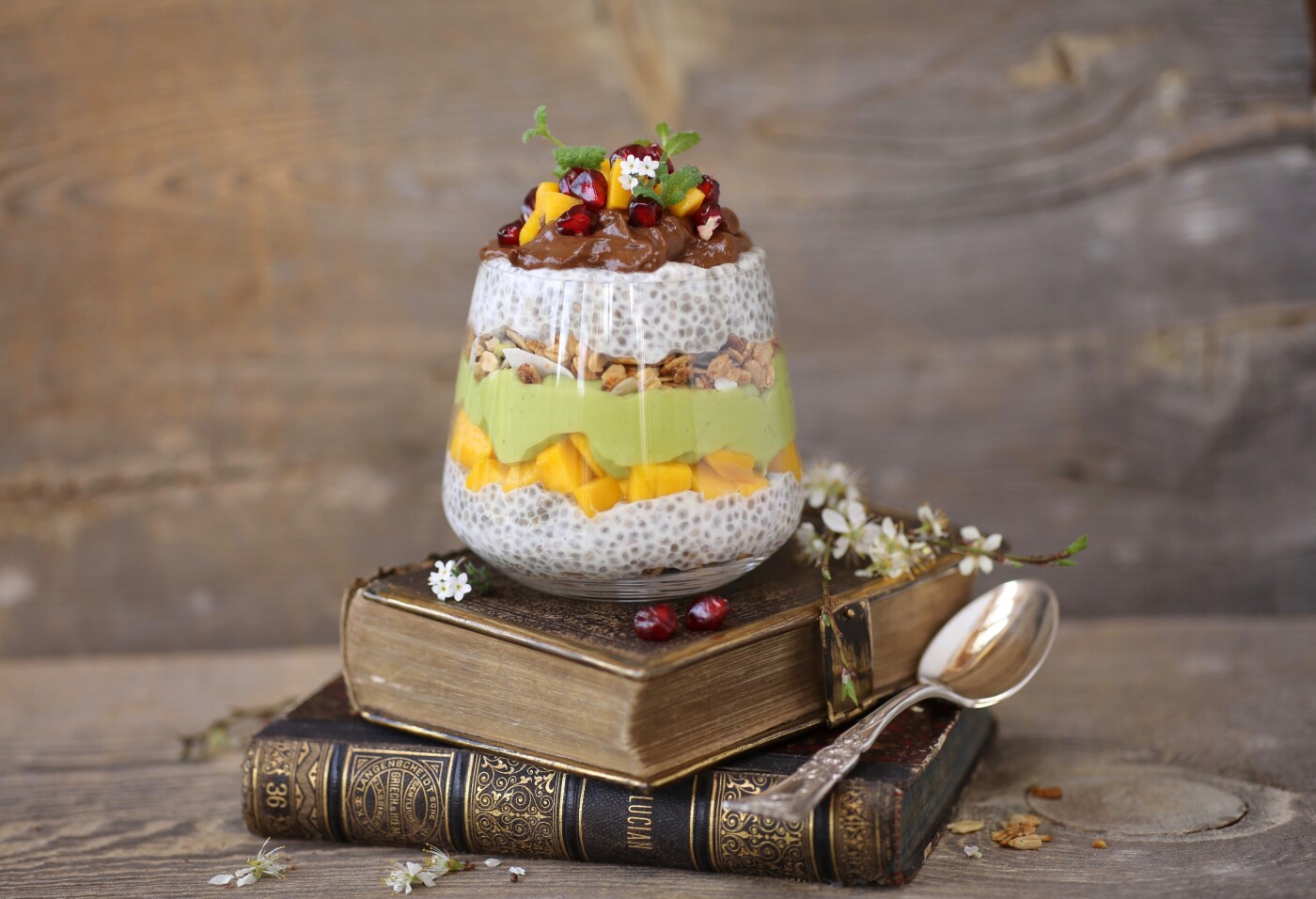 In this picture is Vegan chia pudding with mousse: green one is made from avocado and banana, brown one with addiction of cocoa. Sweetened with honey and topped with fruits.