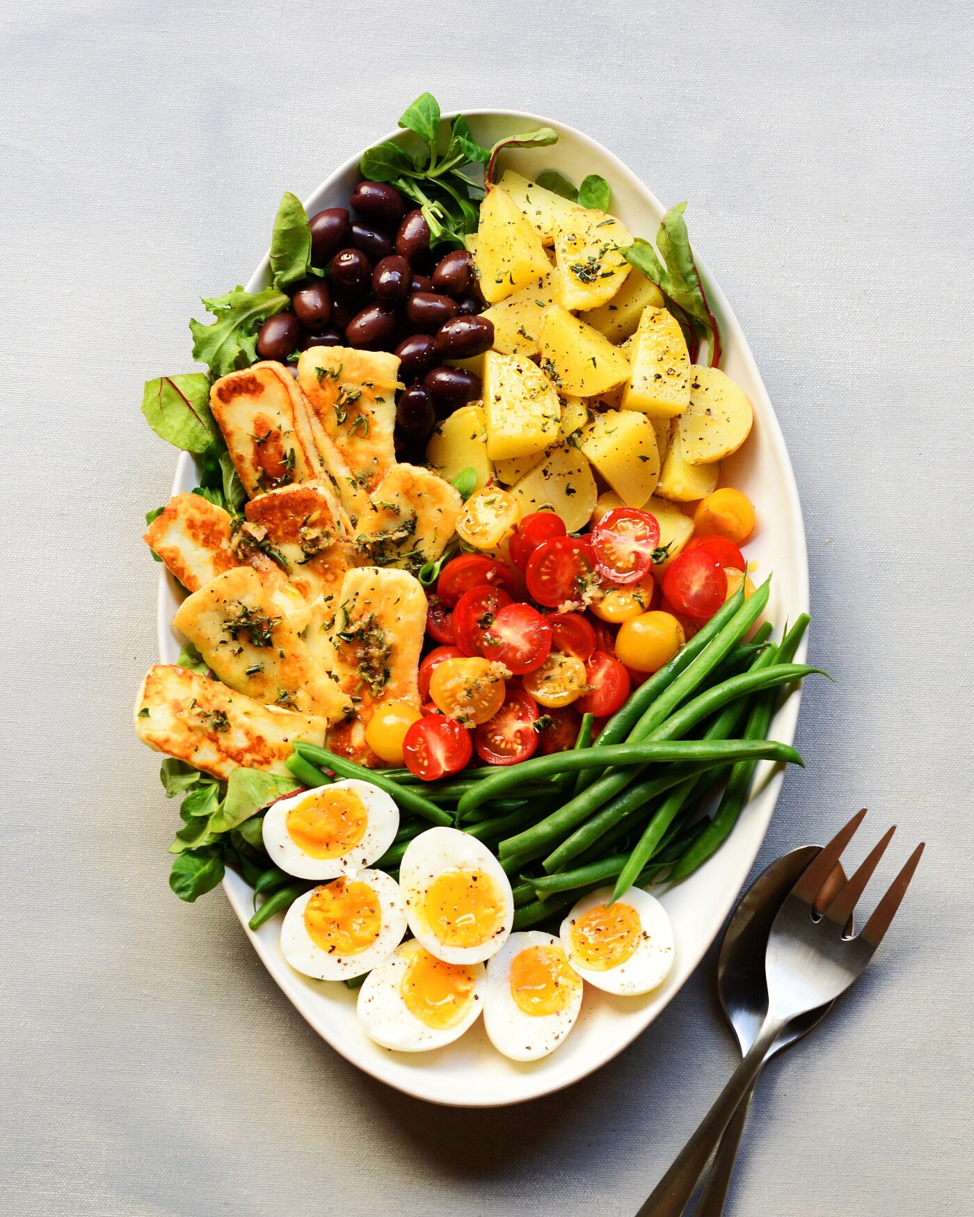 Nicoise salad is one of my favorite summer time meals that appears quite often on the dinner table.  This time I swapped traditional tuna with pan grilled Halloumi cheese.  It has an assemble of in season vegetables such as cherry tomatoes and haricot verts combined with kalamata olives, golden potatoes and 7 minute hard boiled eggs.  The finishing touch is an olive oil dressing whisked with garlic paste, savory herb and lemon juice.  