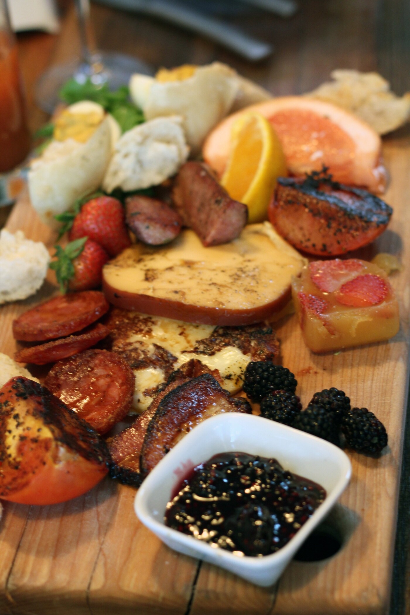 The photo selected is a Brunch Board with hand torn bread, farmhouse cheddar, drunken goat, grilled tomato, maple bacon deviled egg, caramelized pork belly with a mimosa aspic.