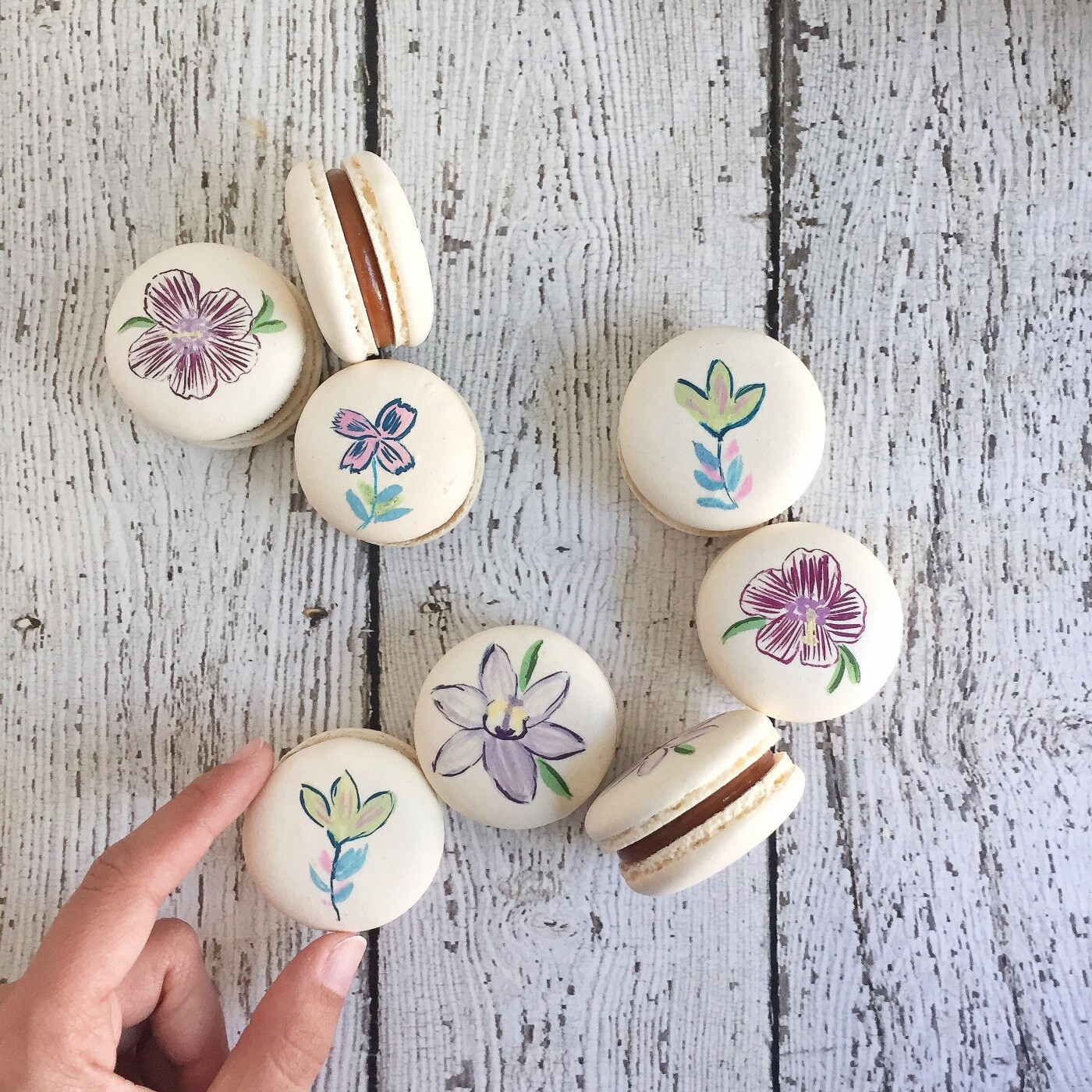 Hand painted macarons for a client. The painted flowers are also the flowers featured in some of the clients products like candles tins and mugs.