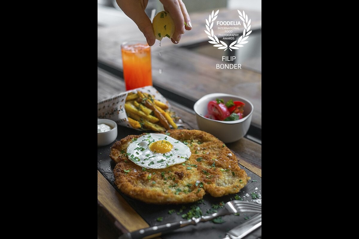  This classical Wiener Schnitzel tastes as delicious as it looks. Top it with fried egg, add tomato salad, baked potatoes, sprinkle it with some lemon juice and you have a perfect and rich meal. <br />
<br />
Shot taken at Zorza Bistro in Warsaw.
