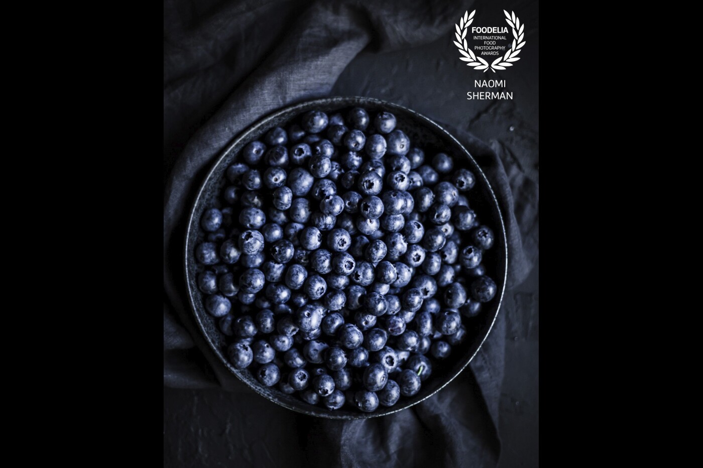 The tone-on-tone look of this image, along with the strong directional light, brings the dusky blue surfaces of the blueberries into the forefront.<br />
Shot in my studio, in natural light.