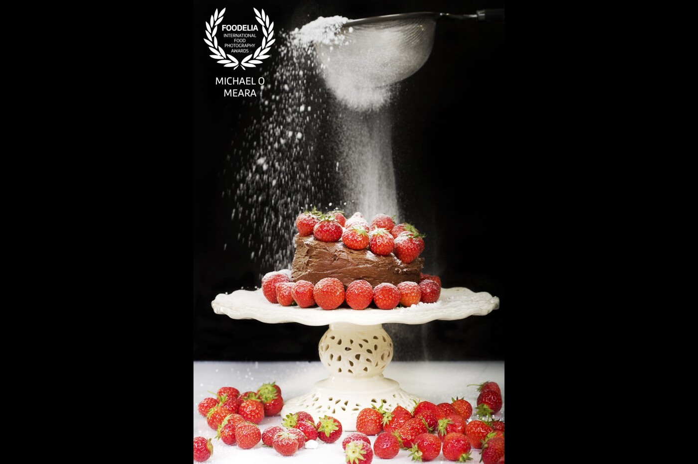 A fun image of a strawberry chocolate cake being dusted with maybe a slightly excessive amount of icing sugar. I wanted to create a cake that anyone could decorate and enjoy making.  