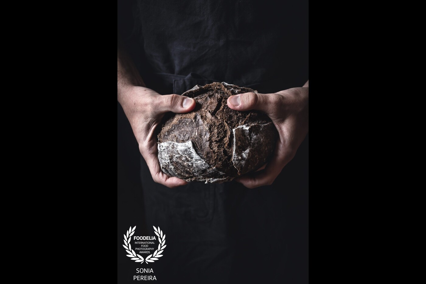 My husband holding a freshly baked carob bread.<br />
What I love the most about it, is the contrast between the bread and the hands and the texture of the bread.<br />
Shot with natural light.