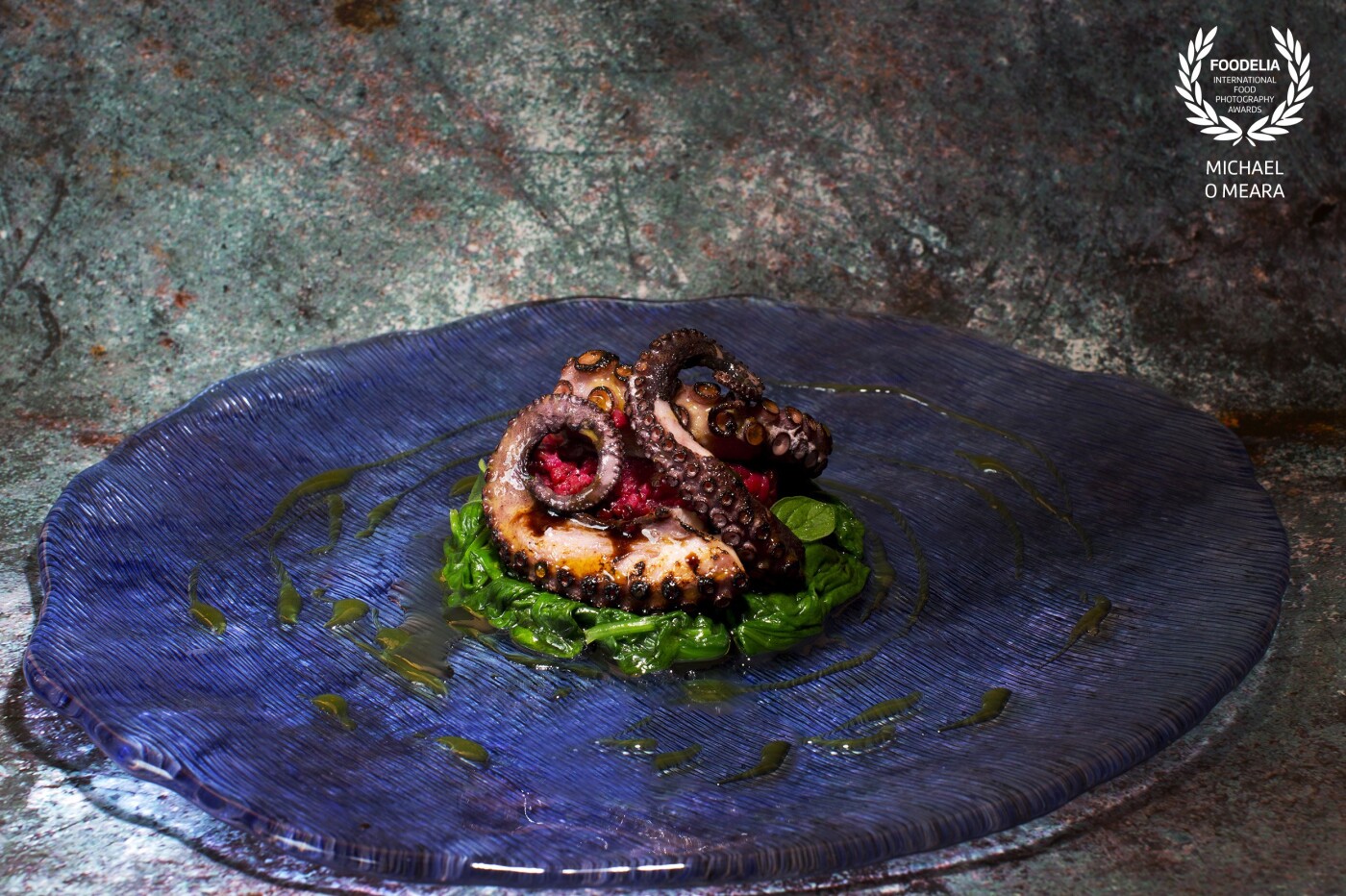 Octopus grilled over a charcoal fire on a little wilted spinach and bulgur wheat made with grated beetroot. The sauce is an orange and white balsamic reduction. 