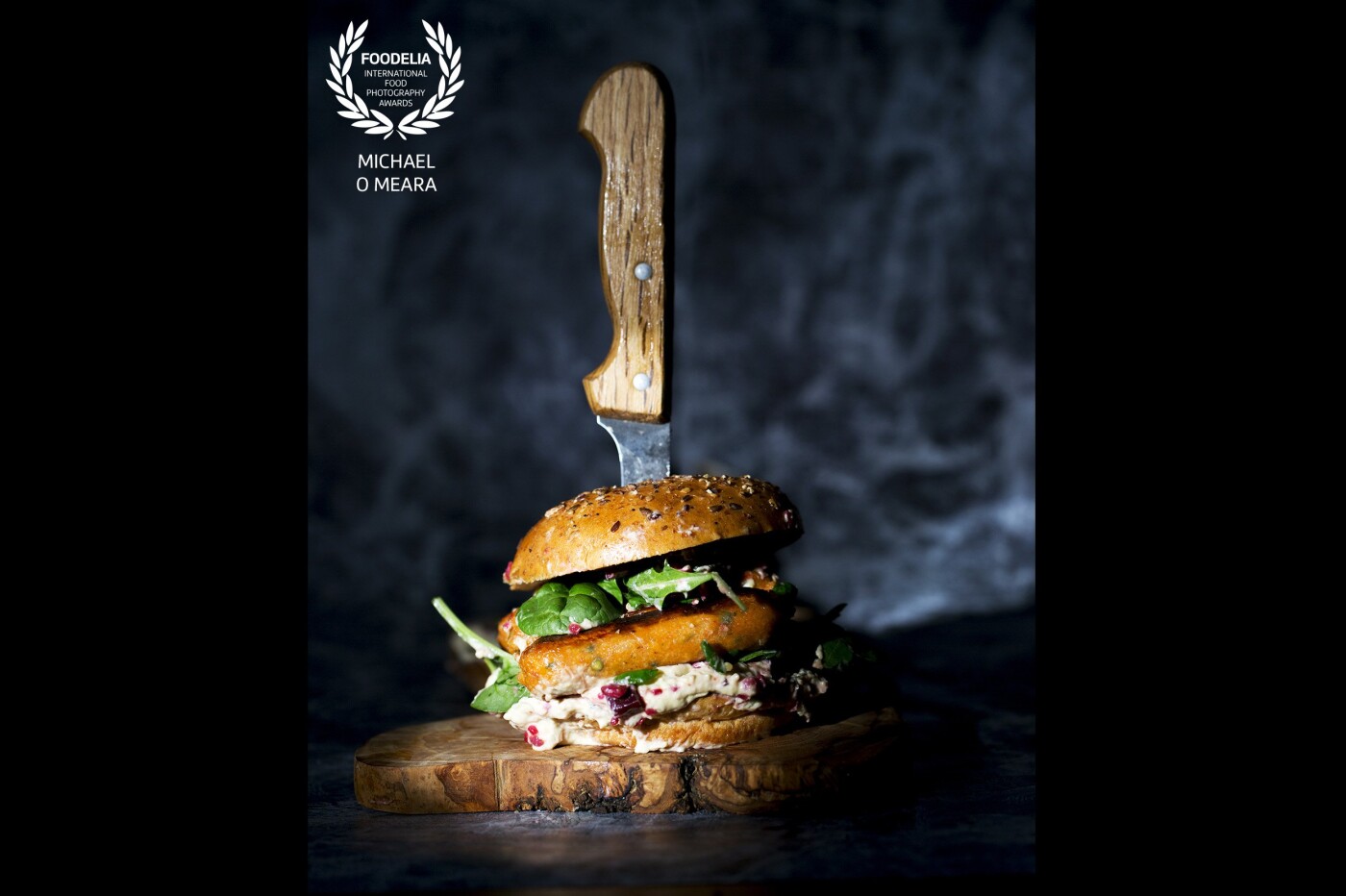 A vegan sausage sandwich with hummus in a multi-seed bun. I wanted to give a gritty, rustic and more masculine feel to this vegetarian sandwich using hard focused light on a smoky background. The sausage ingredients were from a popular value supermarket Aldi. 