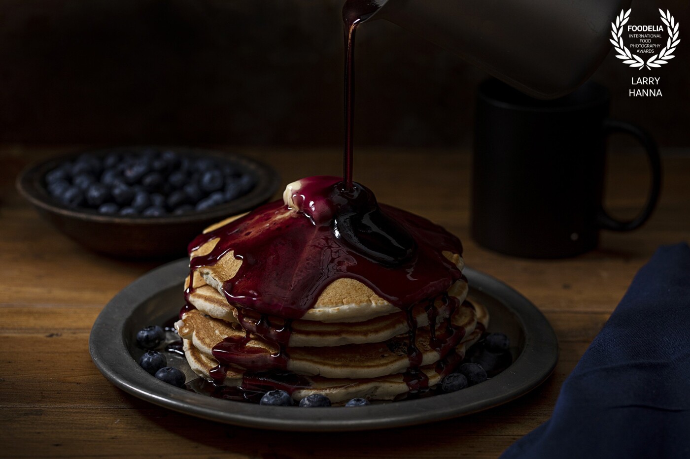 I love a stack of blueberry pancakes in the morning and recently bought some blueberry syrup and loved the way it enhanced the beauty of the pancakes.  I decided that I needed to create an image emphasizing the syrup.  I created this image in my home utilizing strobe light to freeze the action of the pouring syrup.