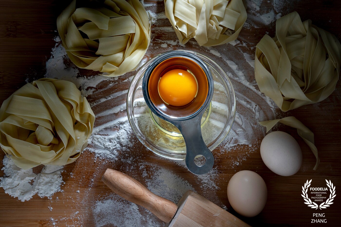 Noodle is one of my favorite food, also the main cuisine theme I photograph.  When I took this picture, I just had bought a new small studio lamp, with which I made a slight beam of light especially focus on the egg yolk,  wishing to strengthen the silky texture of the fresh egg.  Of course, the flour, noodles and the rolling pin on cutting board, all together tell a simple story about how traditional noodles are made.