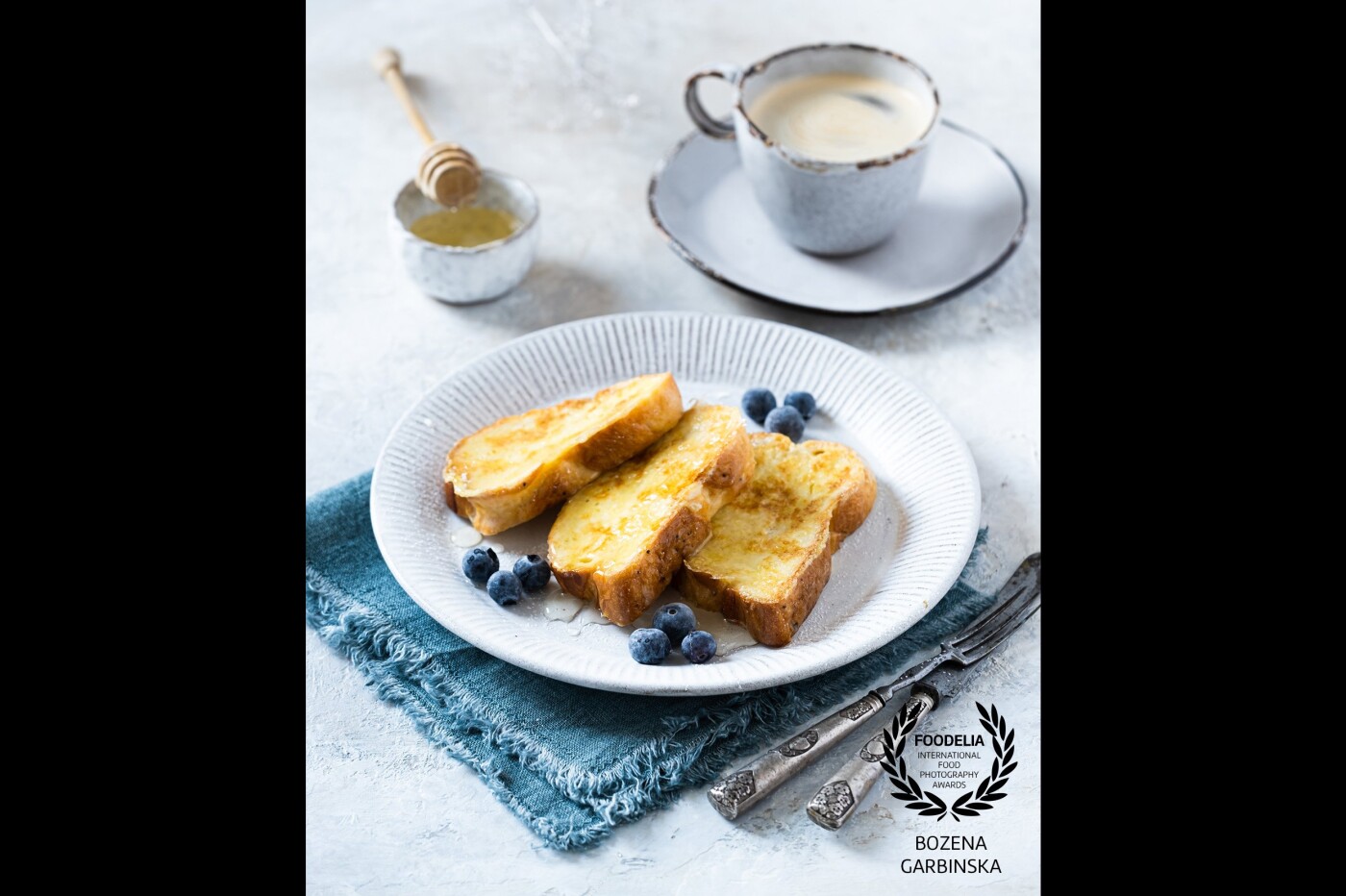 French toast with honey and blueberries it's an ideal breakfast. <br />
Camera: Fuji X-T3<br />
Lens: Fujinon 80 mm<br />
Settings: ISO 80, 1/8 s, f/4.0<br />
Shot using natural light.
