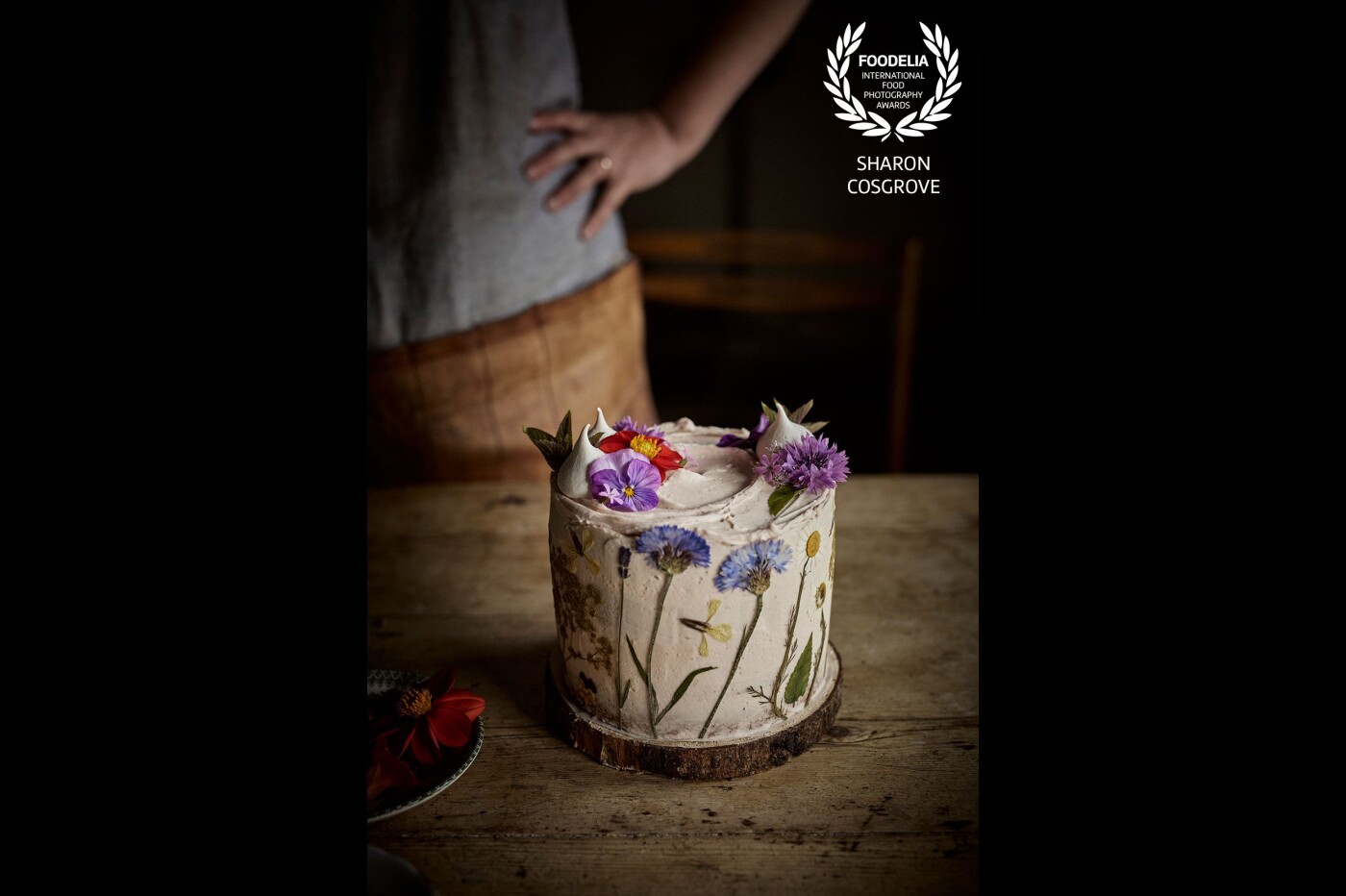 Shot in a cow byre in the Northern Ireland countryside, this edible flower cake was a dream to shoot.  I loved how the natural light spread softly around the cake and how it catches just a glimpse of the chair in the background and the baker looking proudly on at her creation.