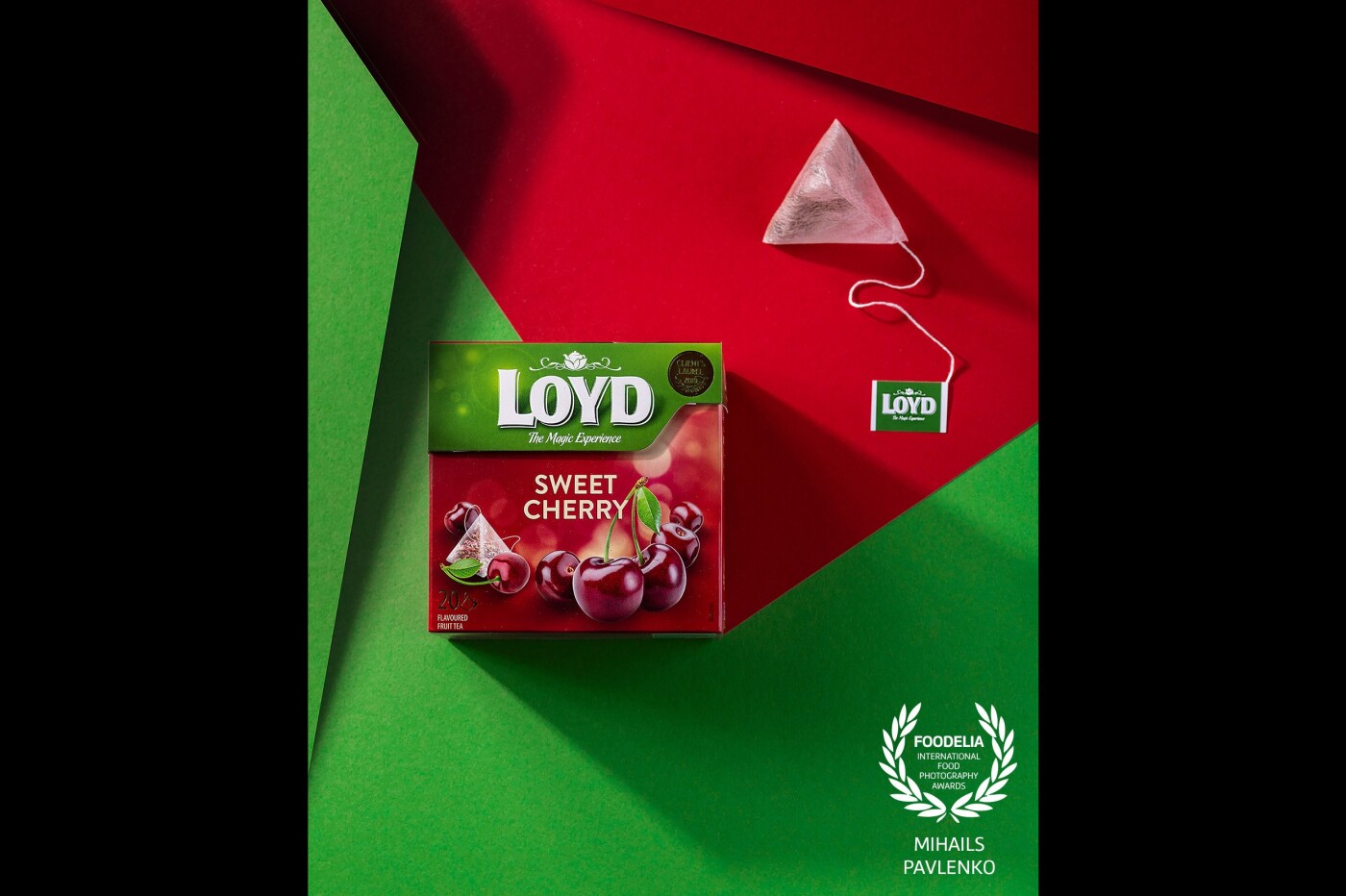 Product shooting of Loyd (@loydtea_official) sweet cherry tea with a triangular tea bag on two-color (red and green) papers. ISO- 125, f/8, 1/160.