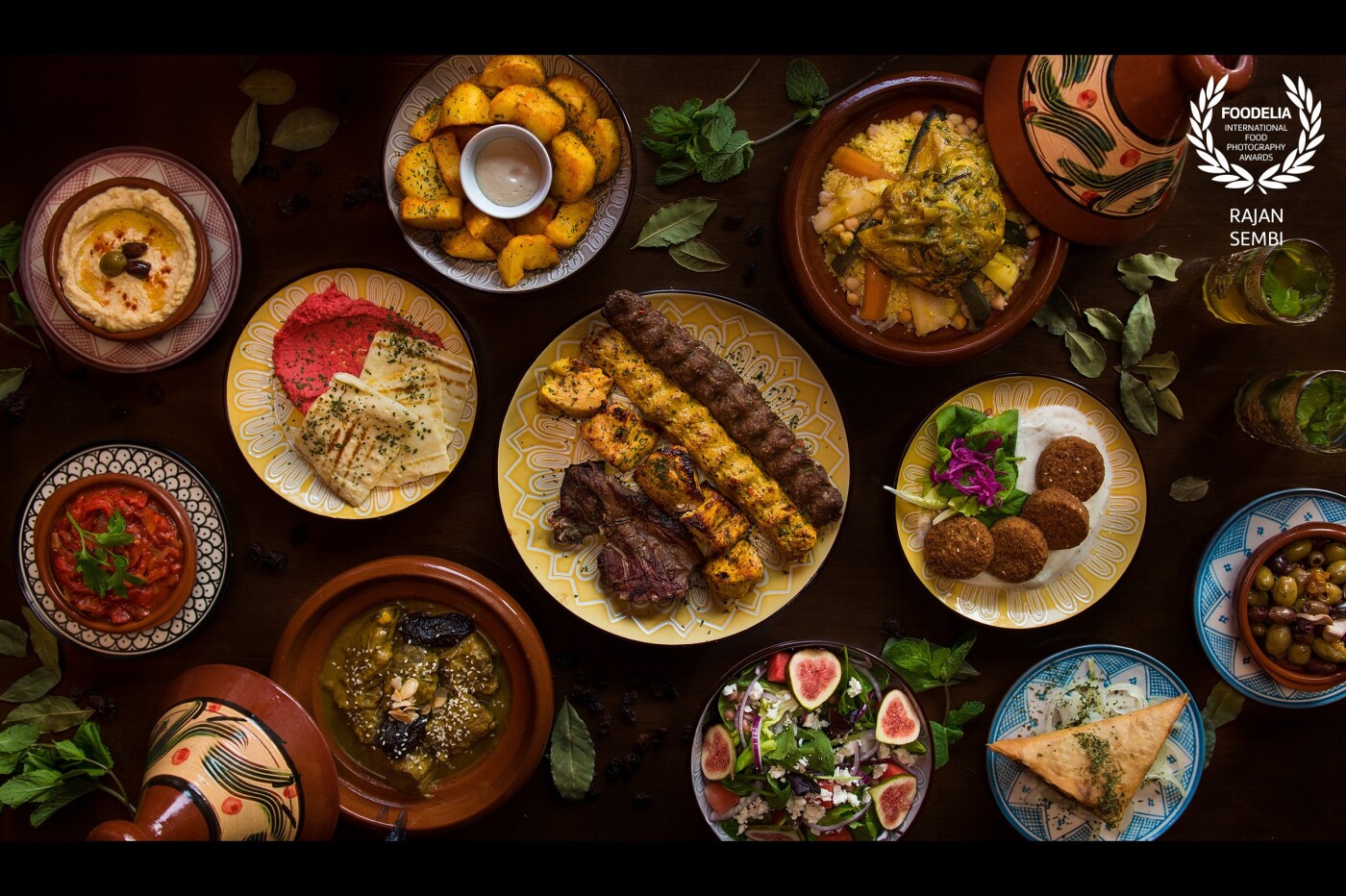 A Taste of Morocco. This photo includes a range of traditional Moroccan dishes including starters and mains. The dishes are surrounded by some key ingredients used in Moroccan cuisines such as dried fruits, bay leaves, and mint. <br />
<br />
I used a Nikon D750 with a 24-70mm lens.