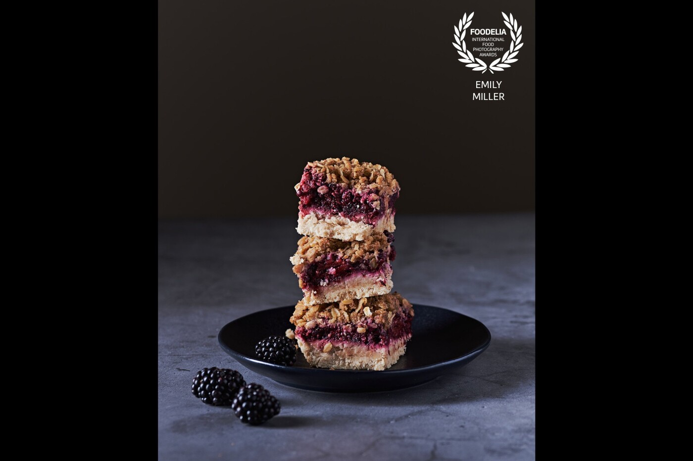 I was inspired to photograph a moody yet vibrant shot of the blackberry crumble bars I made. I stacked them for additional visual interest. To heighten the moodiness and drama I deepened the blacks when retouching.