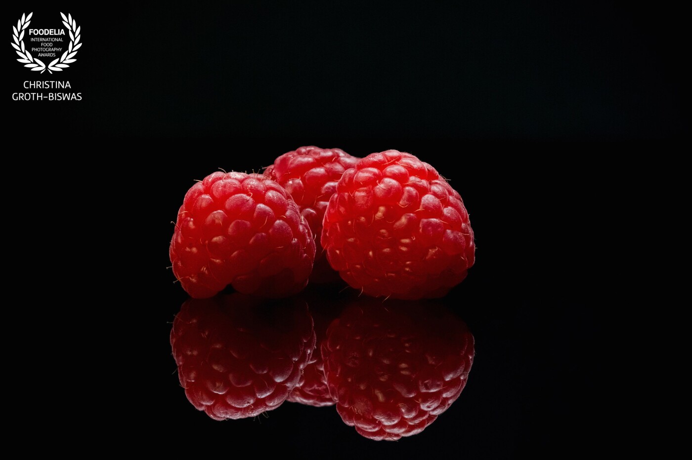Perfectly ripe raspberries and their reflection on black. I did not use any props as they would have distracted the viewer from the beauty of the subjects.