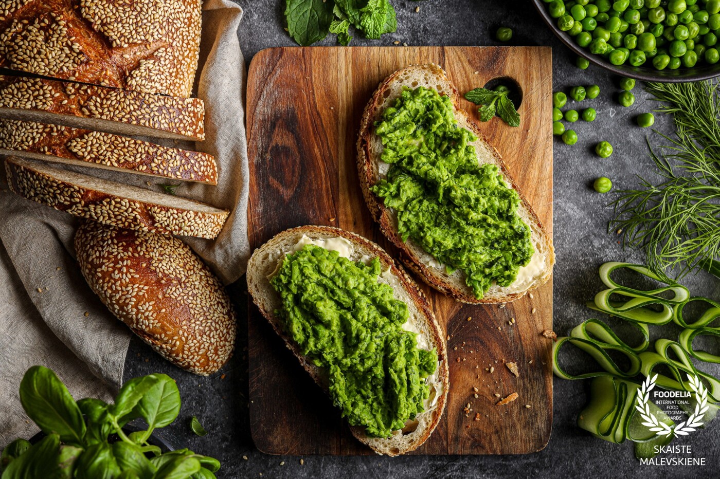 This picture is about textures and shapes. Simple and yet beautiful loaf of bread and greens: peas, basil and mint. Simple is beautiful.