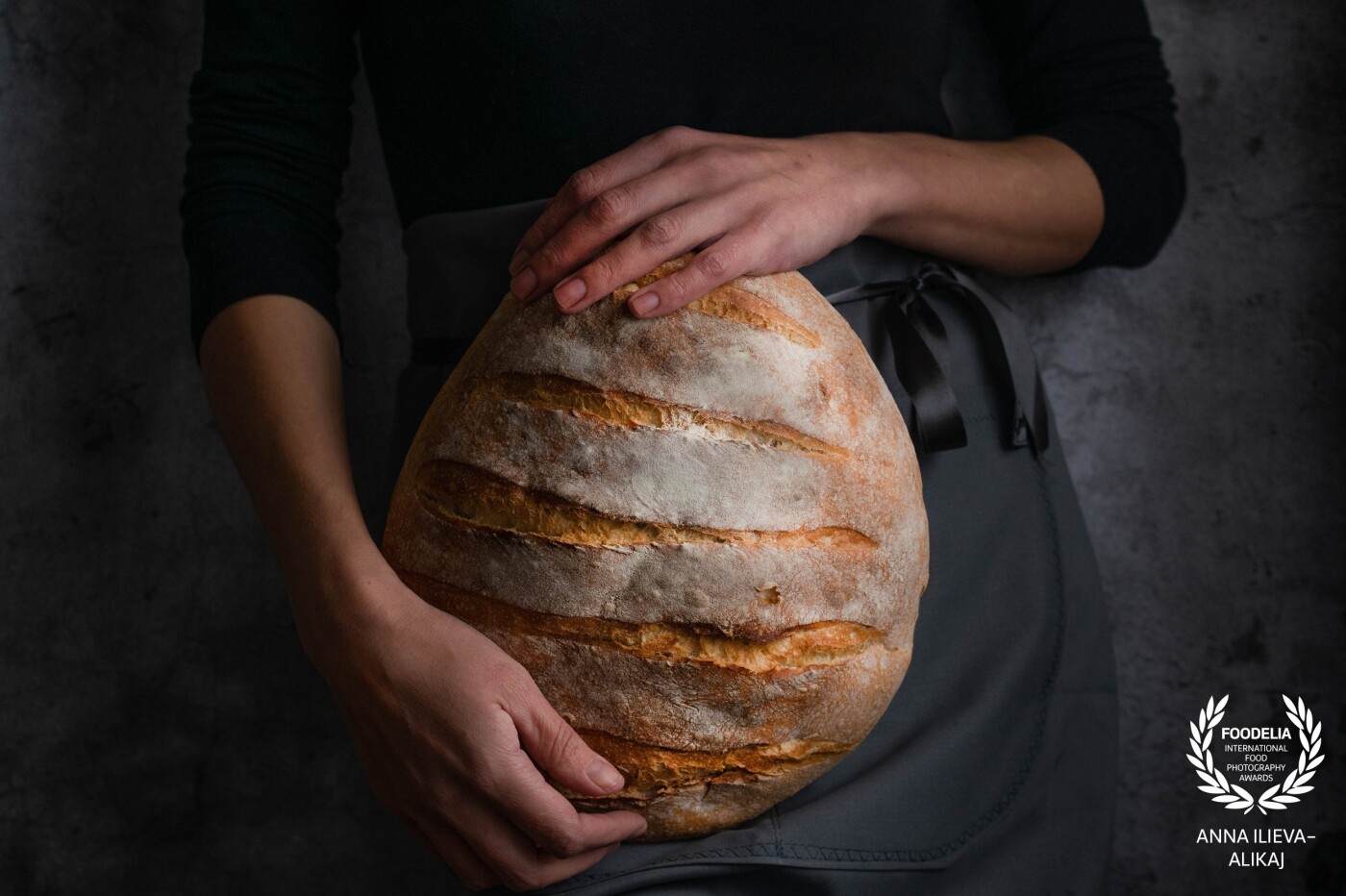 The protagonist of each table - The Bread - held by the strong and loving hands of a woman. I used diffused natural light and moody, dark background with the idea to rapresent the sacrifices of the bakers, who begin their work in the dark to give us our daily bread.