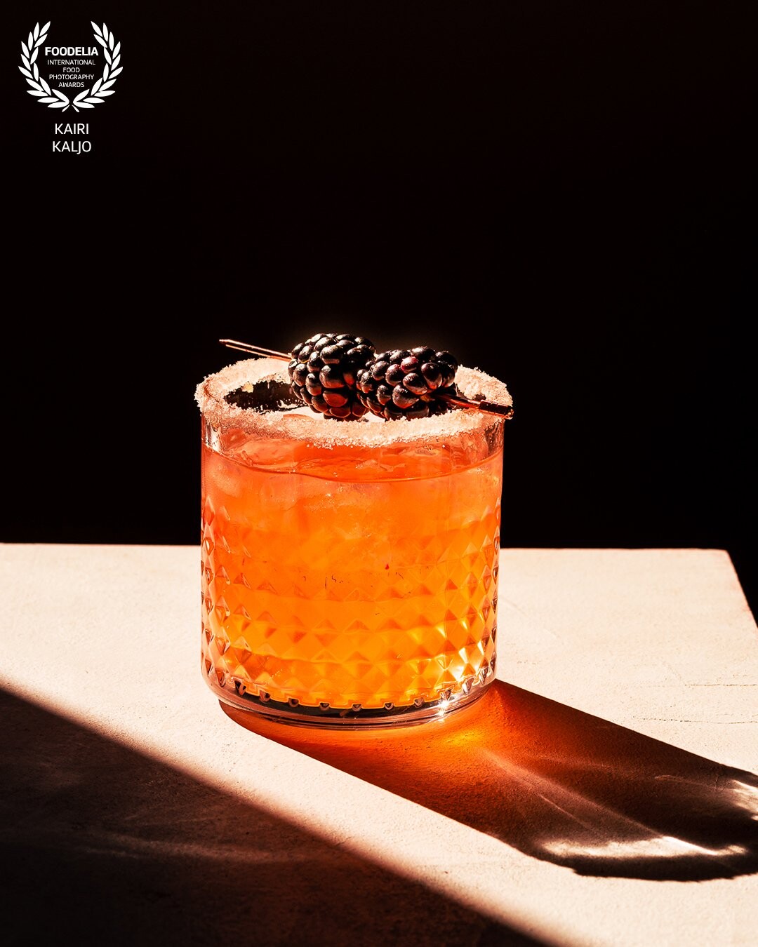 This is a cocktail shot in a magical morning sun. Whilst shot with the direct backlight, the rest has automatically blackened out. One of those impromptu shots with no styling apart from pouring something into the glass and garnishing with some blackberries and placing it into the direct sun light.