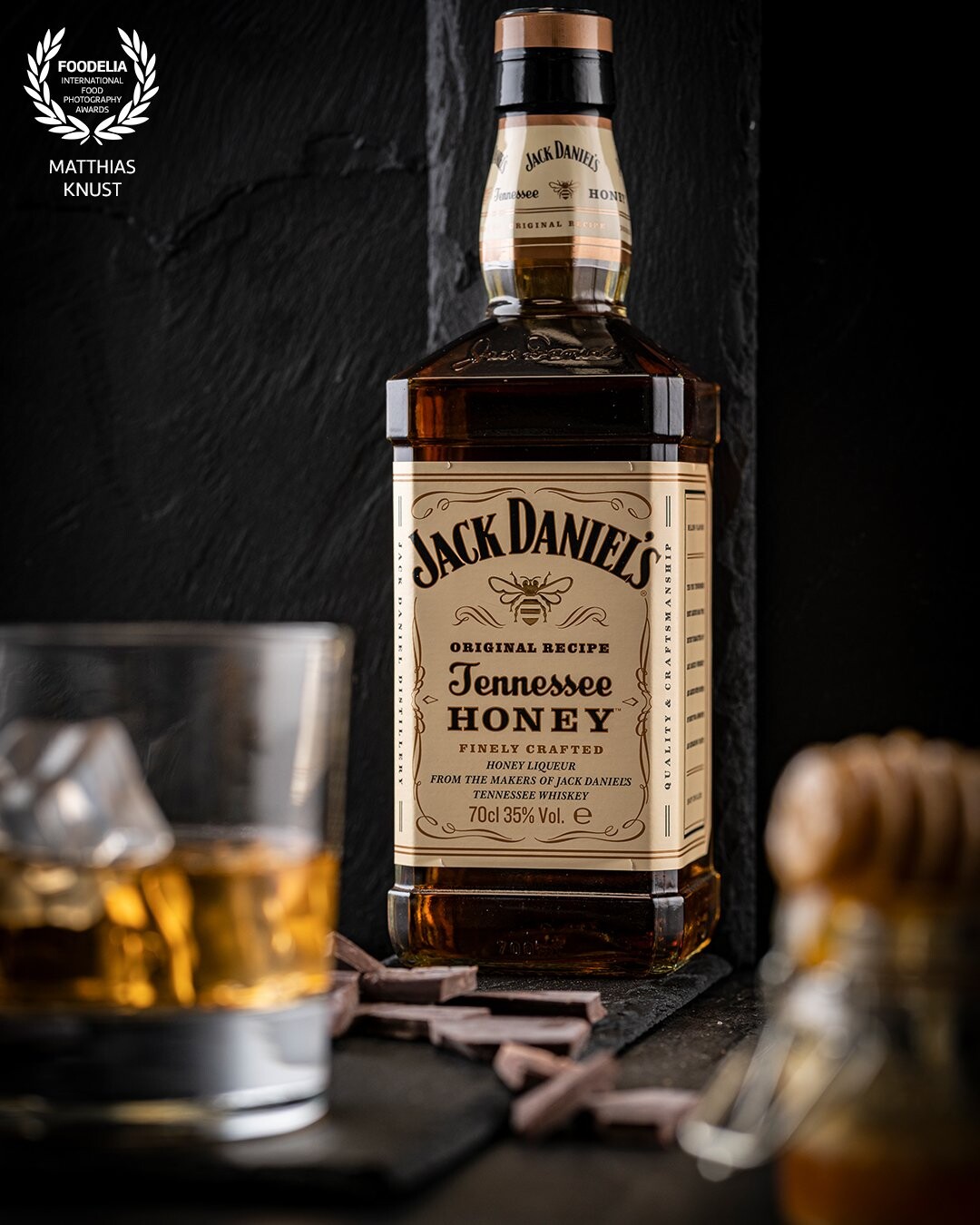 A shot of honey in the whiskey? Why not, simply put the blurring in the foreground of the image with the aperture open, with a little soft light from the left and right side. The contrast between the dark slate and the golden yellow shining whiskey makes this a wonderful eye-catcher. Are you thirsty?