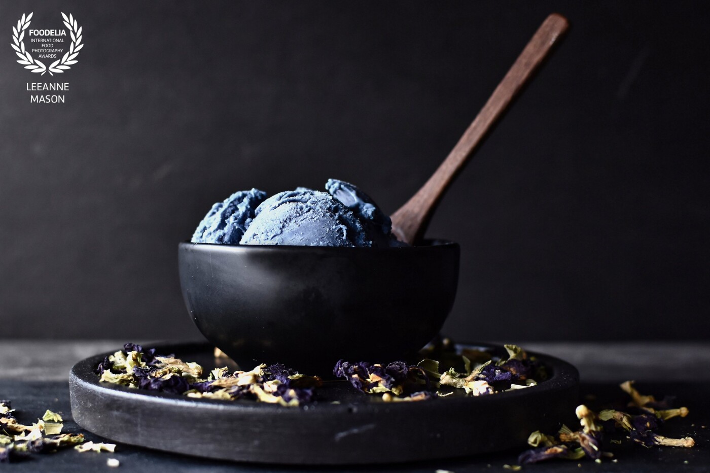 This is my homemade Blue Matcha Ice Cream.  I used dried Butterfly Pea Flowers, removed the stems, milled the flowers and created Blue Matcha powder to use in the recipe.  It has a very different taste and there is something satisfying about creating something unique from scratch.  I scattered the Butterfly Pea Flowers in the scene and placed the spoon diagonally to draw the viewer to the bowl where the hero food sits.  This was shot with a very large aperture and natural light.