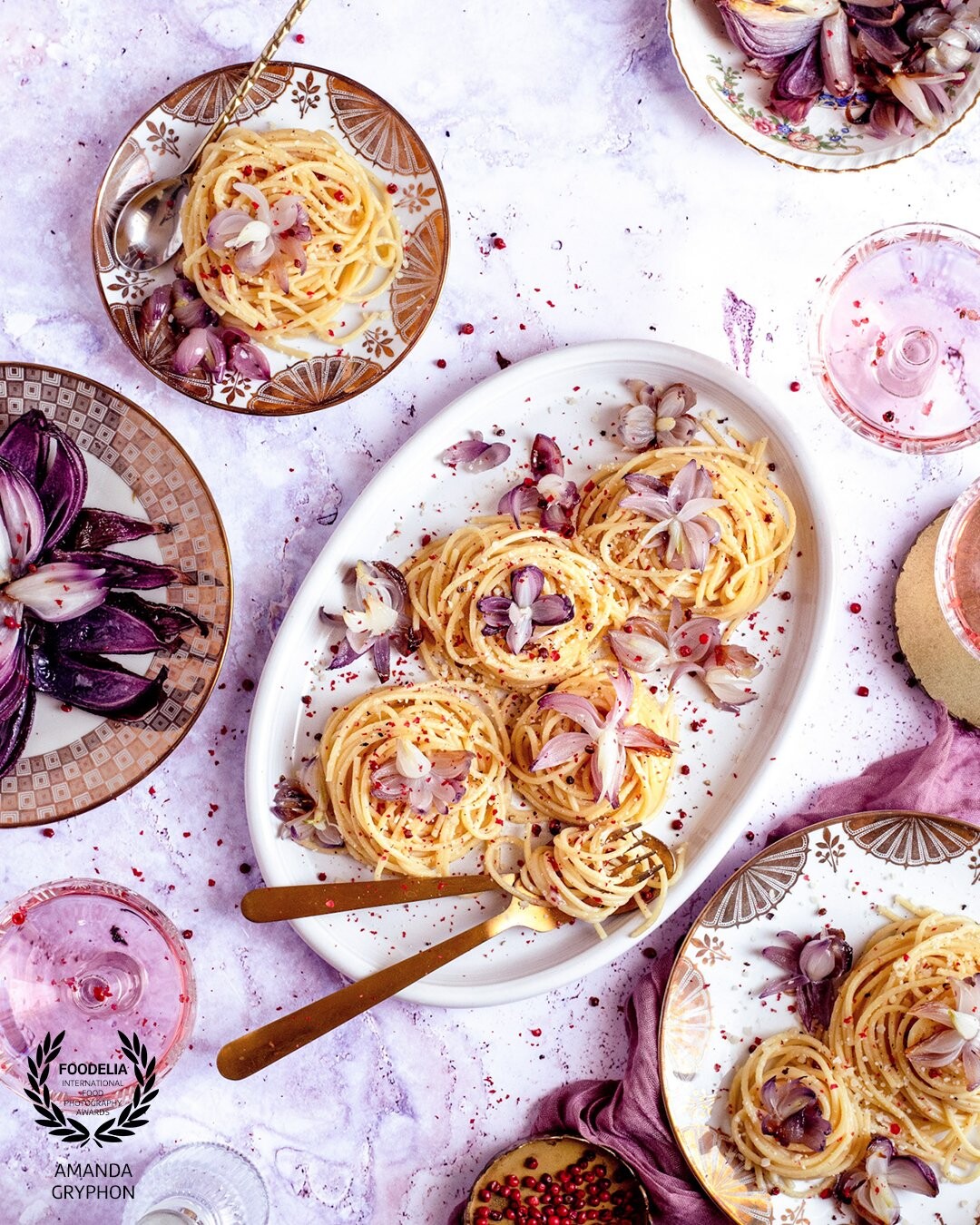 Inspired by cherry blossom season, this pink peppercorn cacio e pepe is blooming with tiny edible flowers carved from red pearl onions in springy shades of pink and purple.
