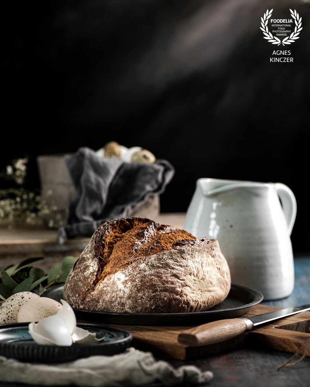 Playing with light to create a moody atmosphere around a loaf of bread, which is being prepared for the dinner table. The dark backround helps to highlight the main element.