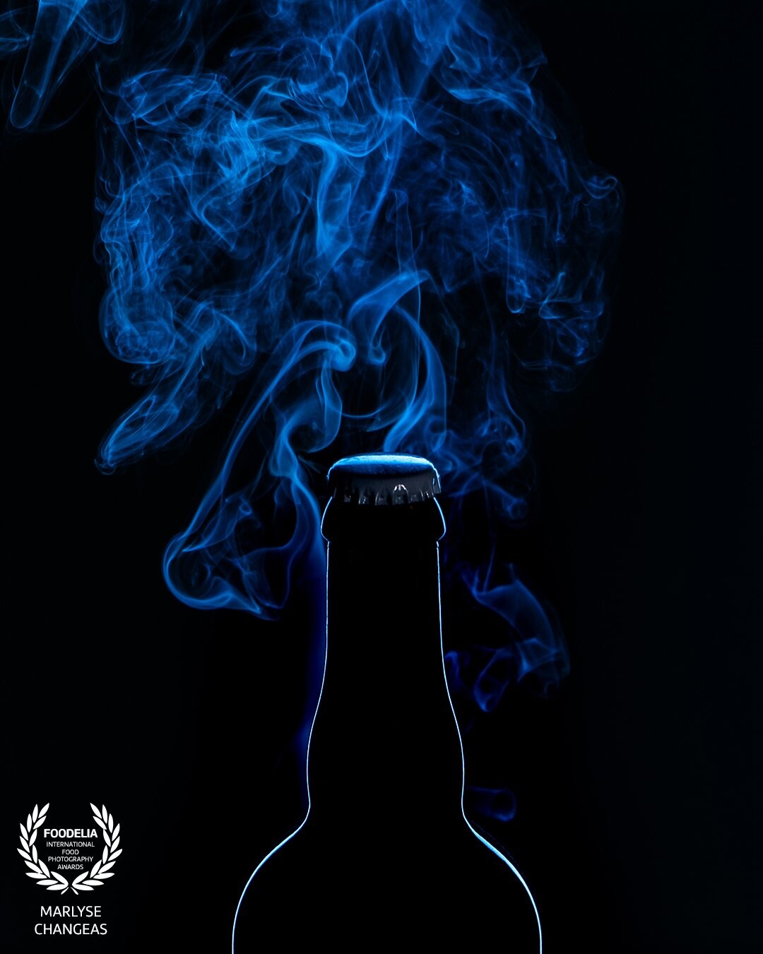 Bouteille de bière, mon intention était de jouer avec la lumière bleue et les mouvements de la fumée. la couleur amène du mystère dans l'image et met en valeur la silhouette.