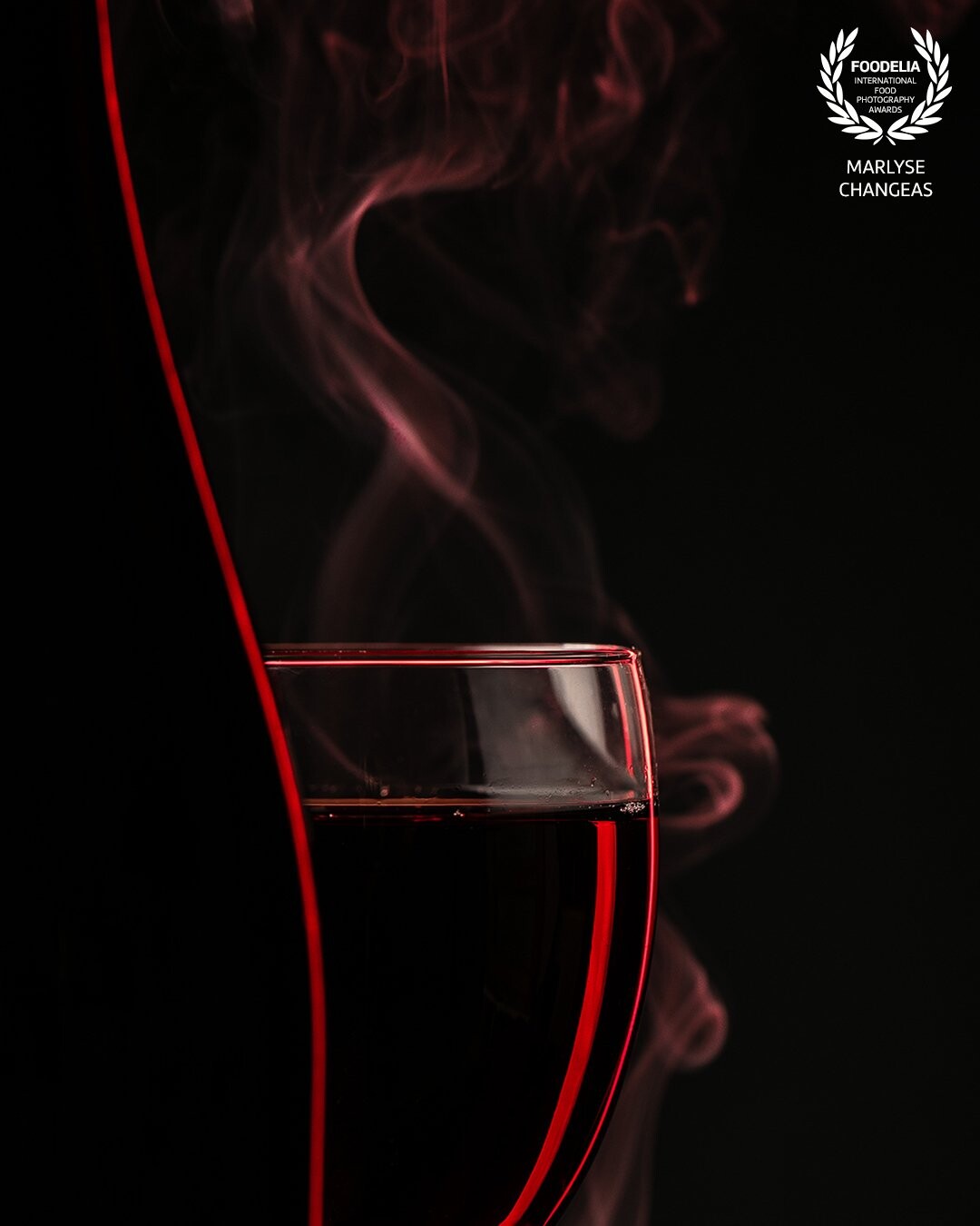 La couleur rouge représente bien la couleur du vin. La lumière rouge met en valeur le mouvement de la fumée et la silhouette du verre de vin. La bouteille à une ligne rouge subtil et légère.