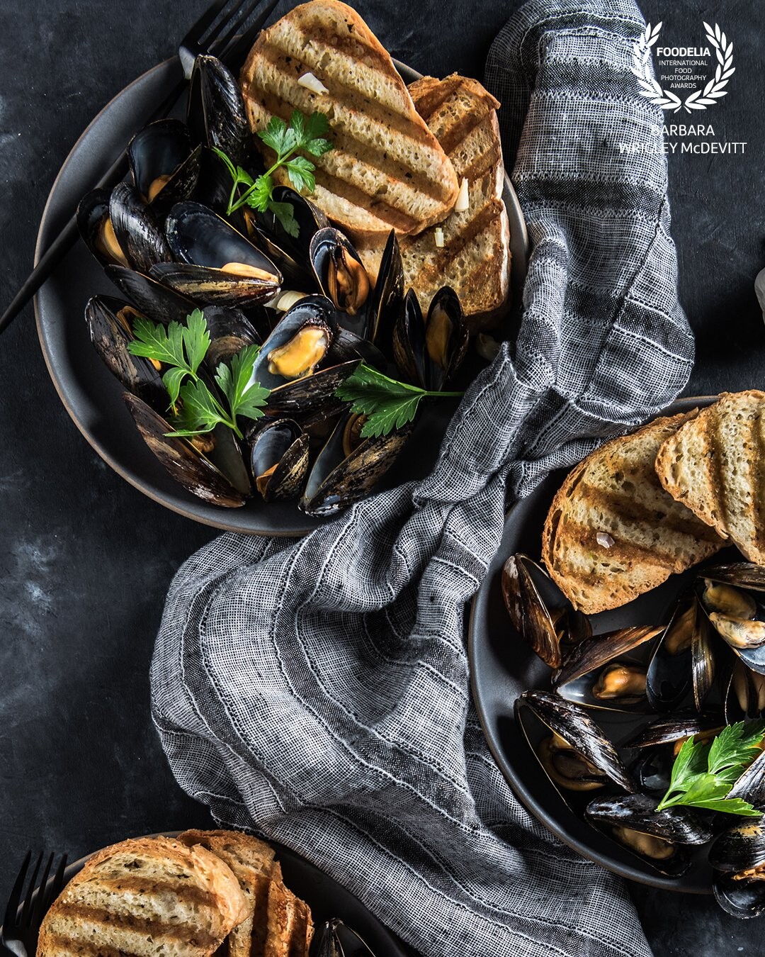 Mussels steamed in a white wine, olive oil and parsley broth.  Crusty bread added to sop up all that goodness.<br />
<br />
Shot on a Nikon D850 with a 24-70 lens.  Profoto B1 artificial light at 7.1 with a rectangular soft box.