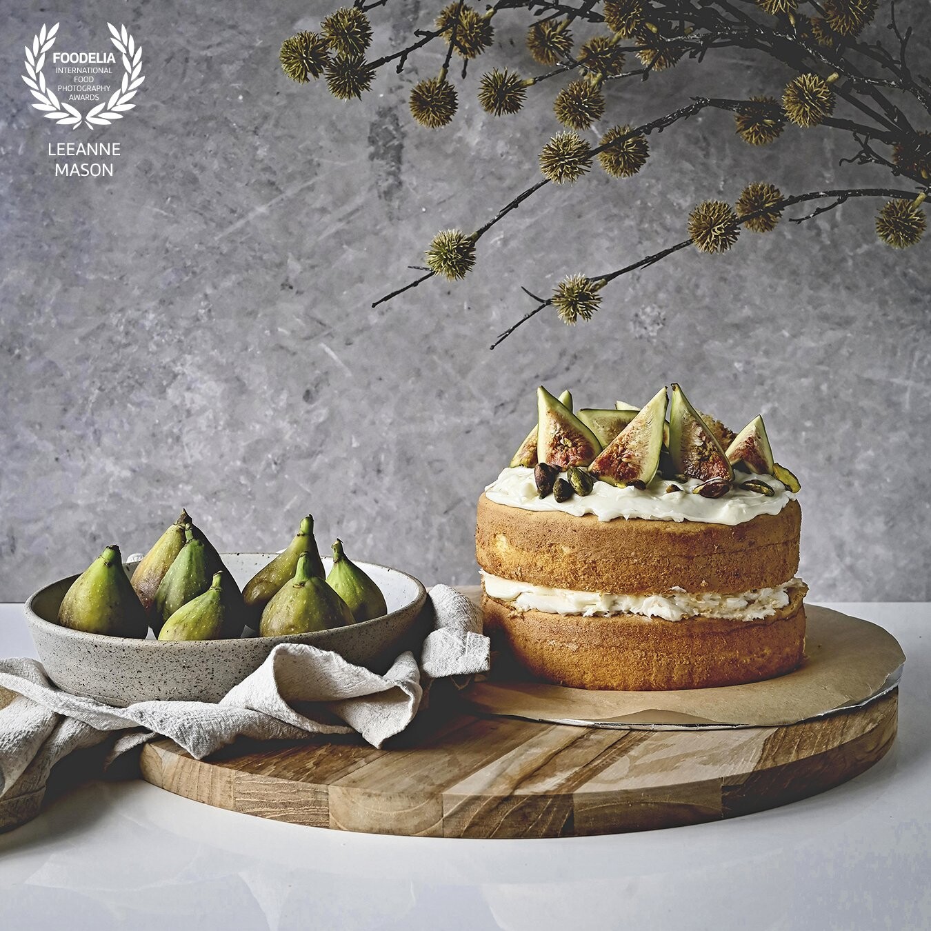 This image was taken during Fig season, I love the shape and texture of Figs, and wanted to highlight this delicious Fig and Pistachio Cake.  Using layers of wood, linen and textured background with a branch of foliage leaning into the frame adding interest.