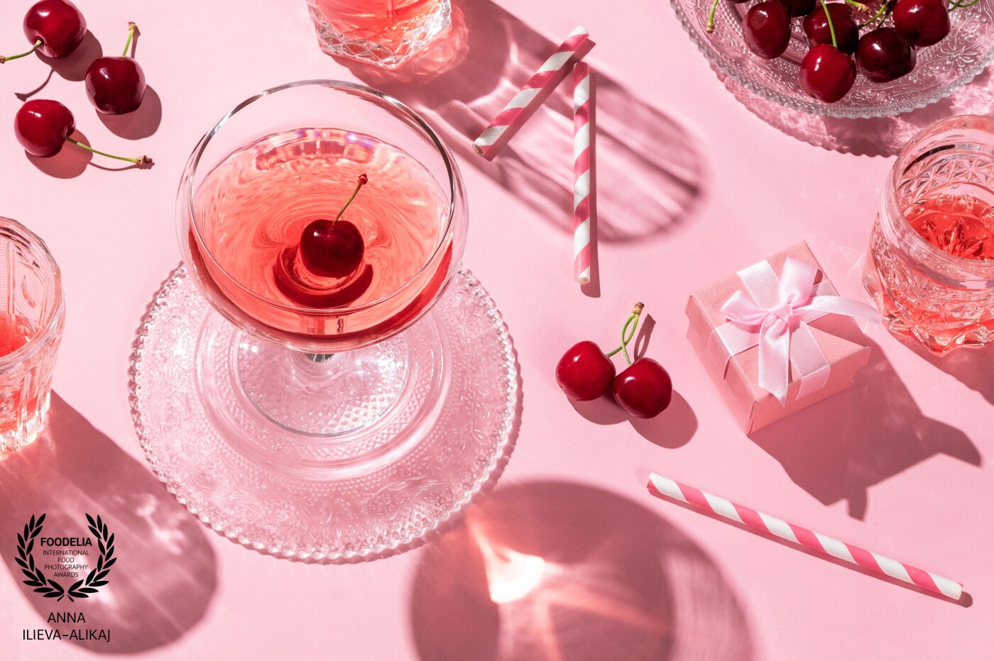 Hopeless, romantic happy hour. The long shadows recall the evening and the cherries, together with the pink background, speak only of love.