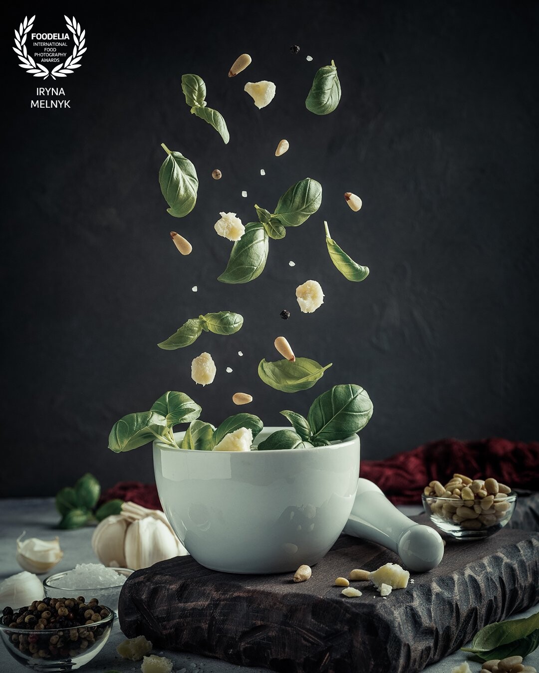 Delicious ingredients for green pesto sauce are falling into a white mortar. Levitation is one of the most interesting types of food photography and my passion